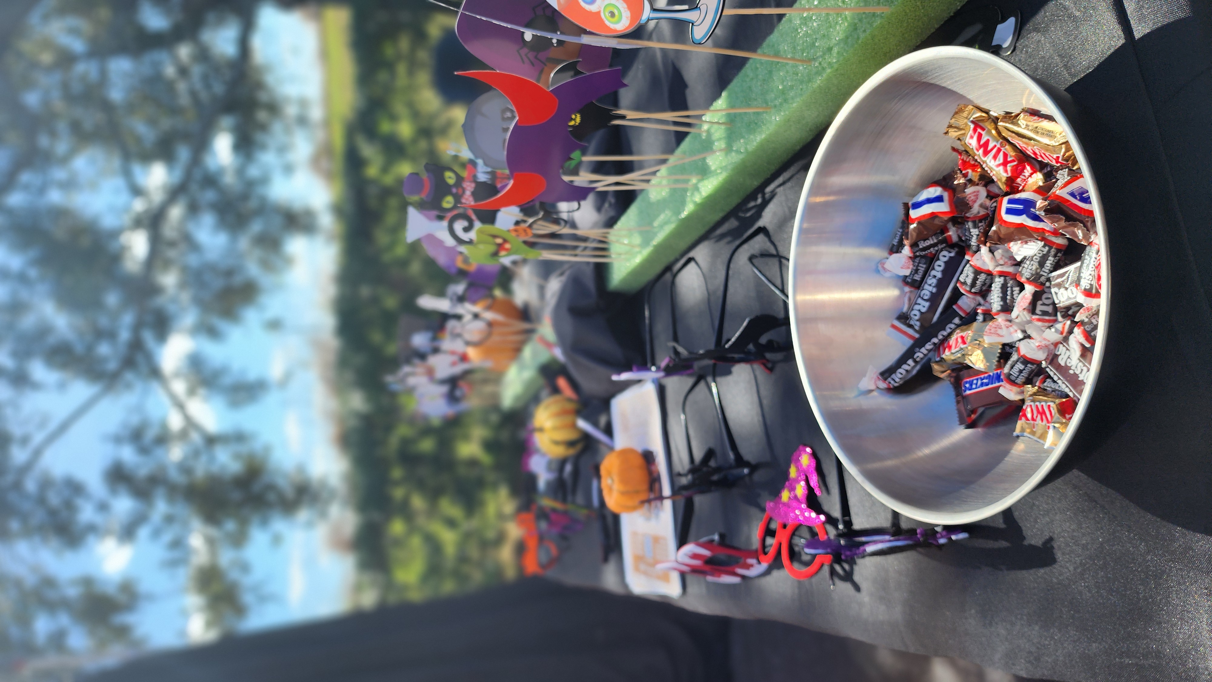 Halloween-themed prop table with hats, signs, and a candy bowl at the Plant City Dinosaur World Trunk-or-Treat photo booth